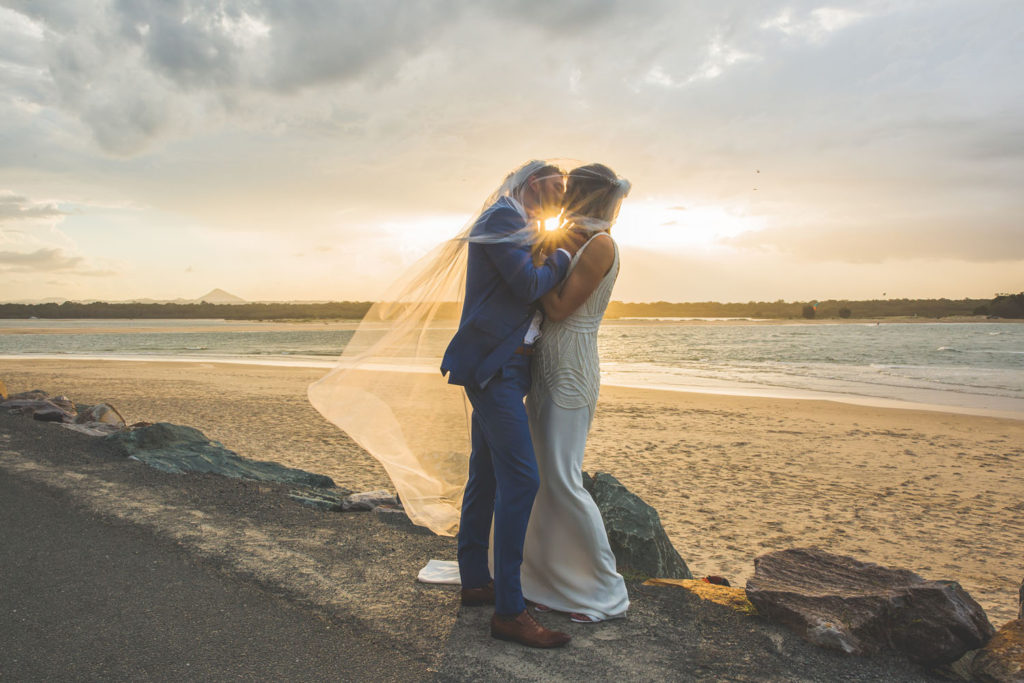 bride and groom kissing at sunset on sunshine coast beach