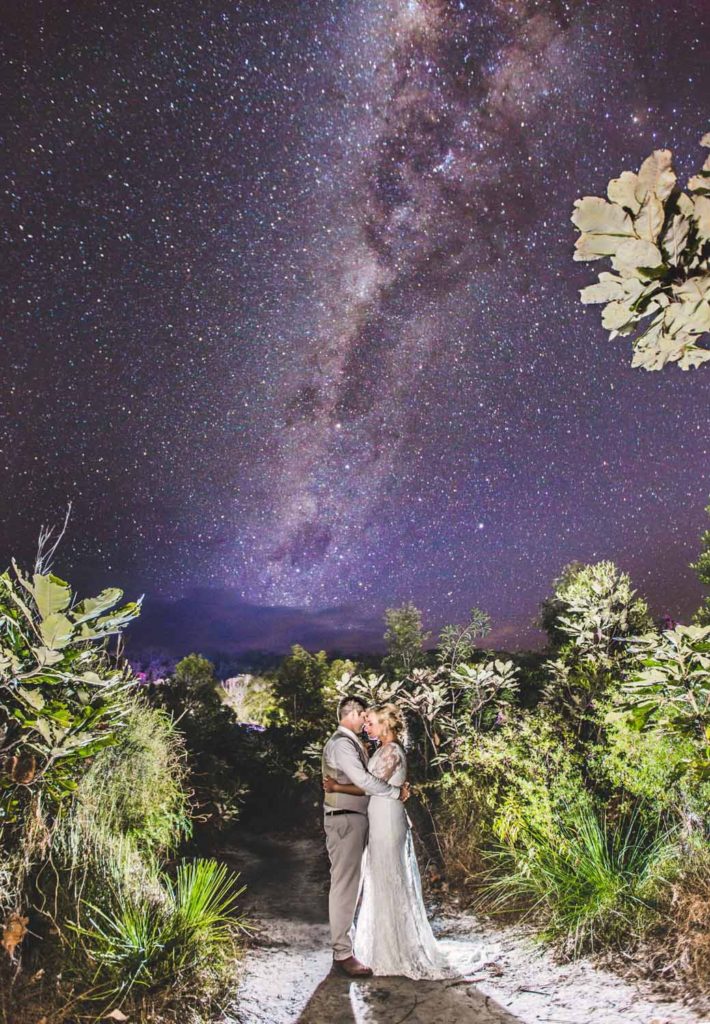 night photograph of bride and groom under starry sky at beach