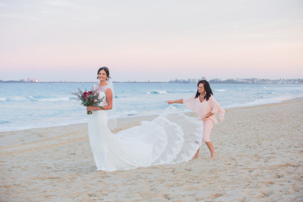 photo of bride with long train on beach at sunset