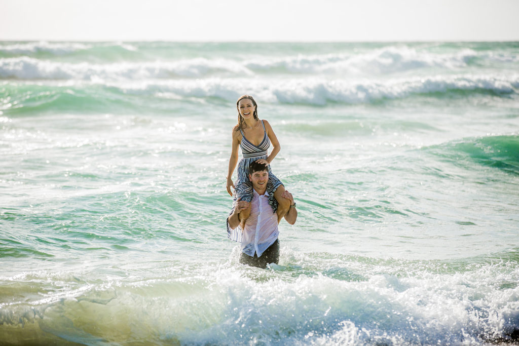fun photograph of engaged couple playing in the surf